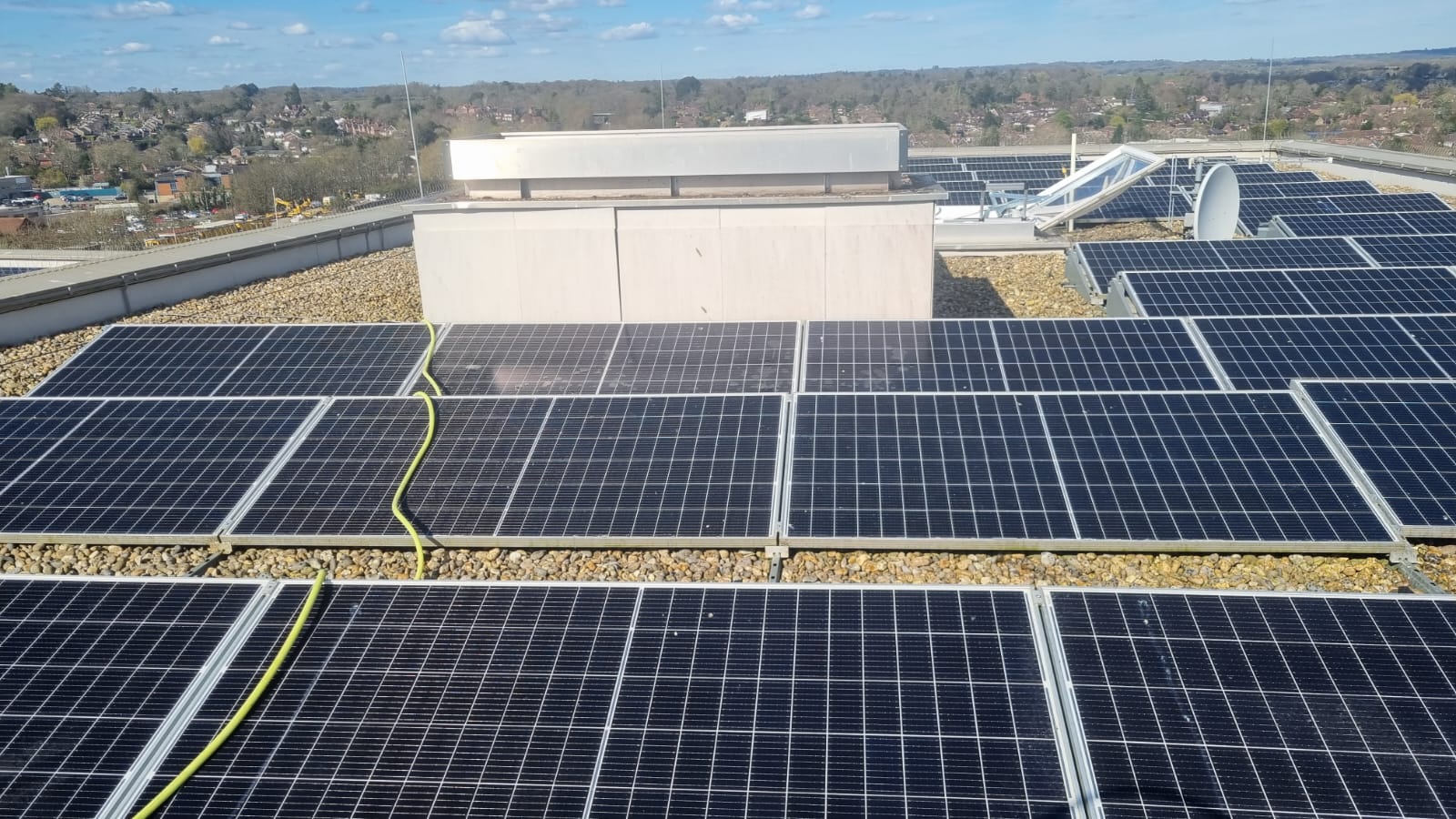 Rows of roof-mounted solar panels being cleaned on a commercial flat roof