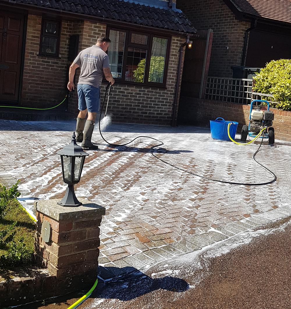 Sam & Son Jet A Drive technician pressure washing a block paved driveway in Sussex